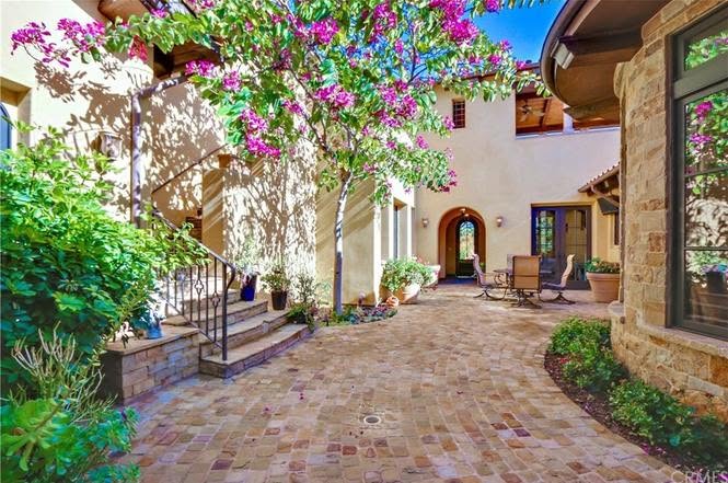 Spanish-style courtyard with smooth cream stucco walls, an arched entry and stone veneer, finished by Dalton Plastering
